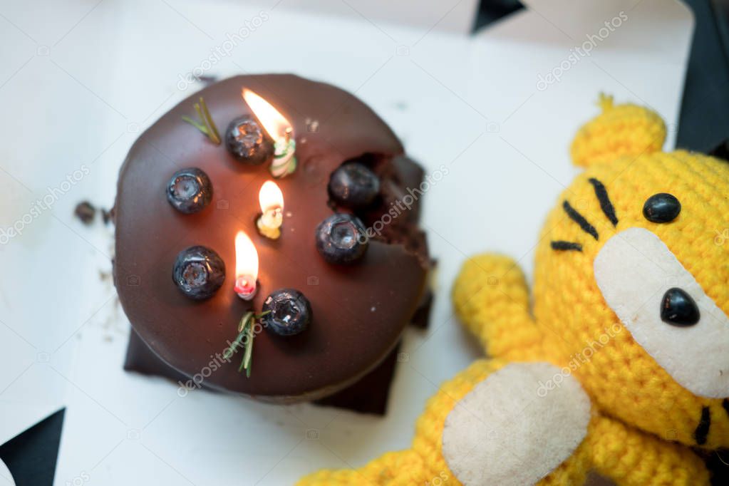 Chocolate dark birthday cake with three colorful lit candles