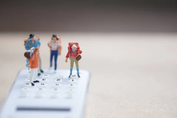 Miniature people backpacker standing on white calculator for calculate money and time to travel. Concept of travel planning and save cost