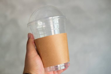 Tek kullanımlık plastik bardak cam kahverengi kağıt kol ile tutan adam