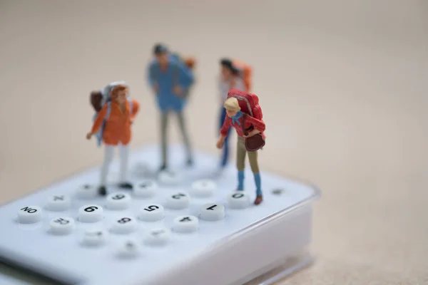 Miniature people backpacker standing on white calculator for cal