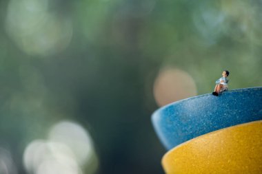 Minyatür insanlar, mavi bardakta oturan kadın 