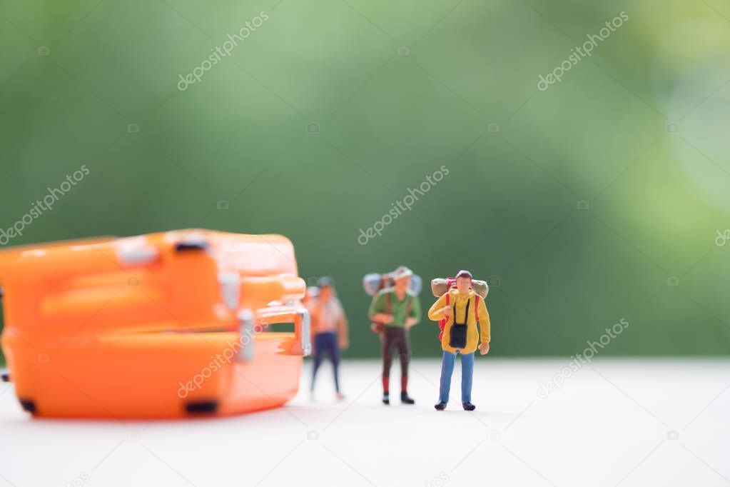 Miniature people: Backpacker standing front suitcase