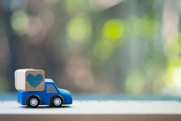 Toy blue pickup truck delivering blue heart