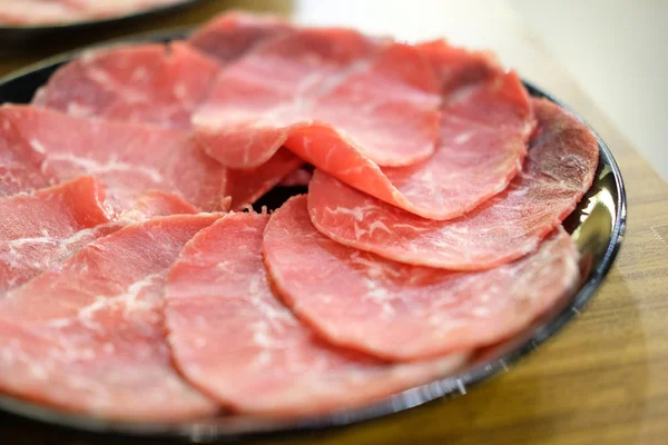 Roh geschnittenes Fleisch auf dem schwarzen Teller — Stockfoto