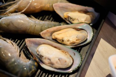 Siyah tepsi üzerinde taze çiğ karides ve midye