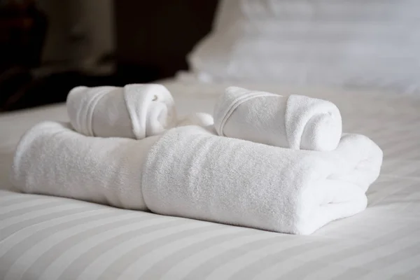 Pilha de toalhas de banho brancas na cama lençol — Fotografia de Stock