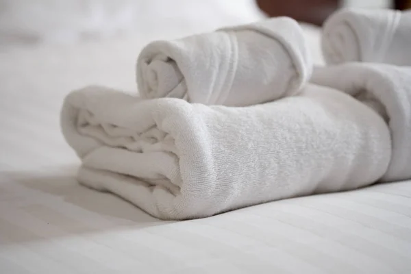 Pilha de toalhas de banho brancas na cama lençol — Fotografia de Stock