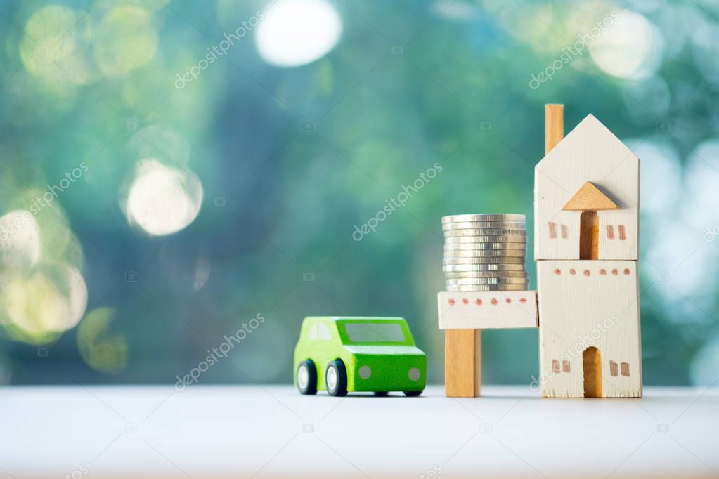Close up of coins and toy home toy car on wooden table on blur b