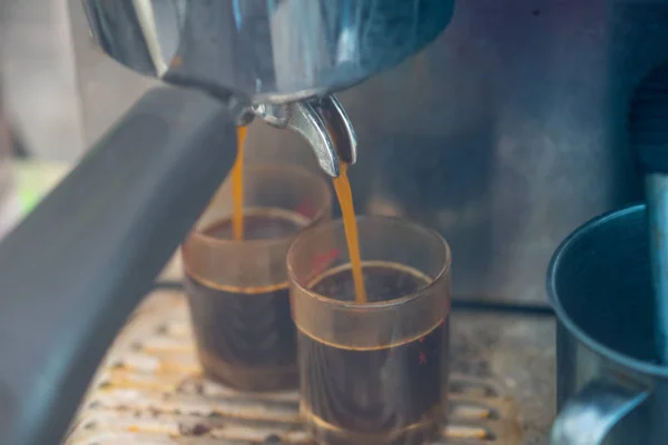 Close-up van espresso gieten van koffiemachine naar shot glas. — Stockfoto