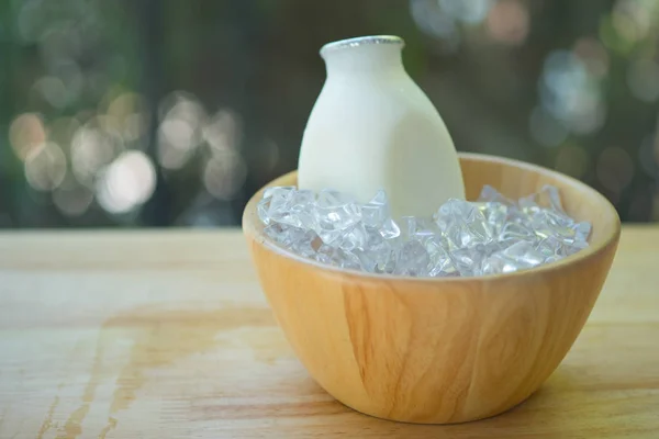 Свежий молочный пластиковый флакон на деревянной чаше — стоковое фото