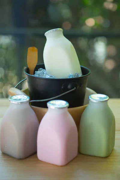 Olika av färsk mjölk smak i flaskor på träbord — Stockfoto