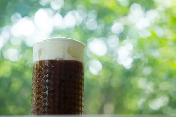 Es kopi dalam gelas dengan busa susu dengan latar belakang alam — Stok Foto