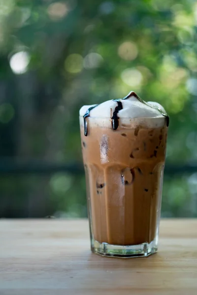 Iced coffee mocha with milk foam and chocolate sauce in a tall g