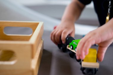 Evdeki masada ahşap oyuncakla oynayan tatlı bir çocuk.