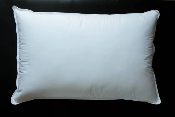 Close-up of white pillow isolated on a black background.
