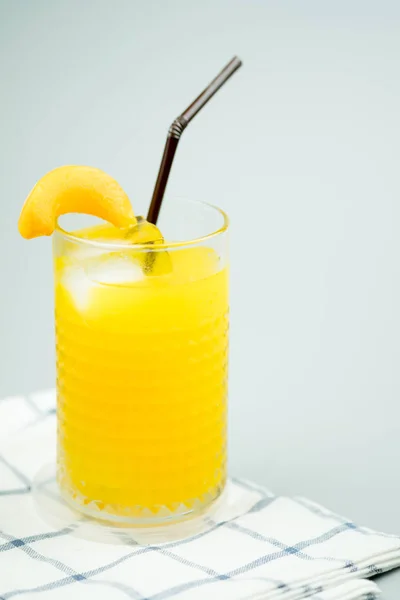 Jugo de naranja dulce recién exprimido con cubitos de hielo y decoración con rebanada de melocotón —  Fotos de Stock