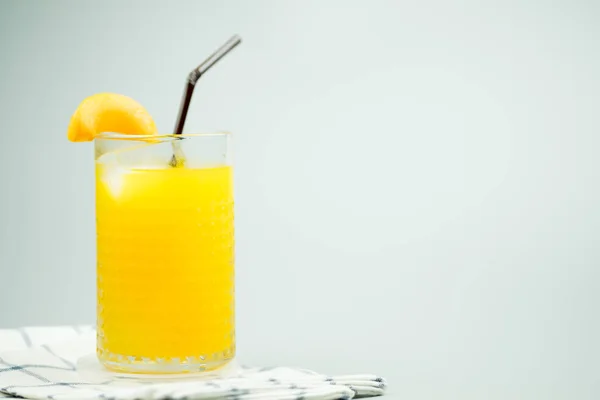 Freshly squeezed sweet orange juice with ice cubes and decoration with slice peach — Stock Photo, Image