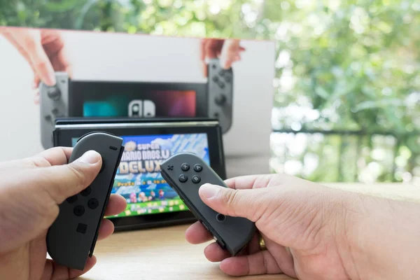 Bangkok, Thailand - June 10, 2019 : Hands holding Nintendo Switch gaming controllers for playing digital video games Mario deluxe switch for fun leisure entertainment — Stock Photo, Image