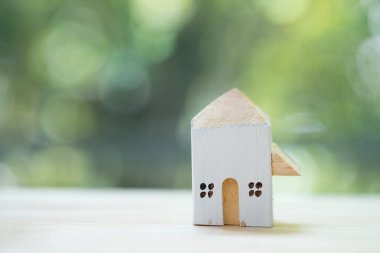 Güvertede ahşap ev modeli, yeşil bulanık doğa geçmişi var.