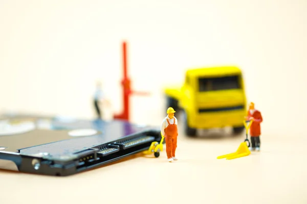 Personas en miniatura: Trabajadores tirando de una transpaleta con placa de circuito en movimiento para enviar a reparar. Concepto empresarial de mantenimiento —  Fotos de Stock