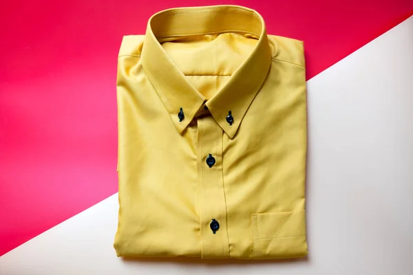 Yellow shirt on red and pink background. Concept of buy and sell