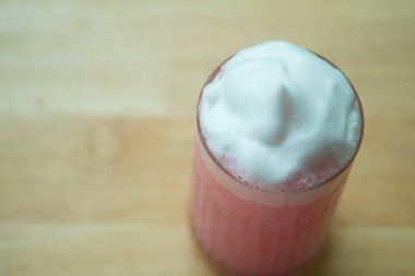 Cam süt köpüğü ile buzlu pembe süt.