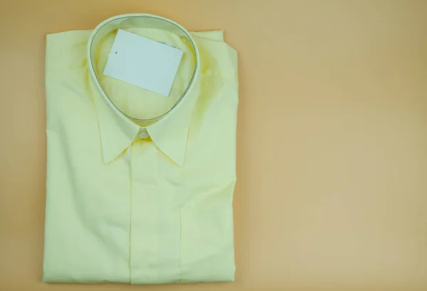 Homens camisas amarelas dobradas em um fundo amarelo . — Fotografia de Stock