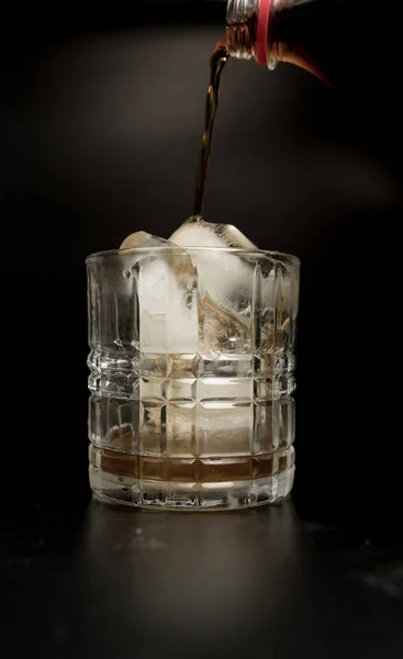 Pouring cola into glass with ice cubes — Stock Photo, Image