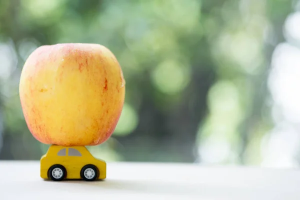 Apple on yellow toy car.  Back to school