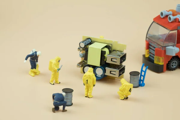 Tiny figures of chemical team in hazmat suits examining