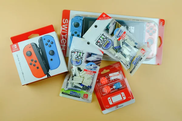 Bangkok, thailand - 11. august 2019. souvenir aus japan auf gelbem hintergrund vom besten freund. rote und blaue Nintendo Switch Joy-con Controller und Spielzeugeisenbahnblock — Stockfoto