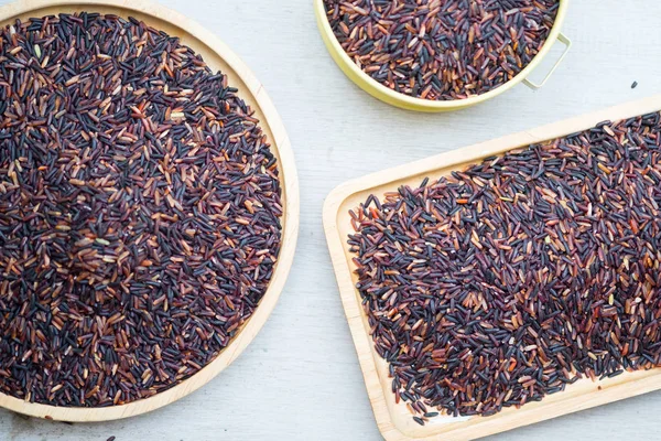 Uncooked black rice on wood tray