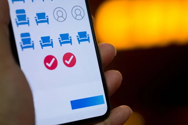 Hand zeigen digital reservierte Sitzplätze auf mobilen Smartphones. Online-Buchung und Zahlungskonzept — Stockbild Zeige digital reservierte Sitzplätze auf dem mobilen Smartphone — Stockfoto