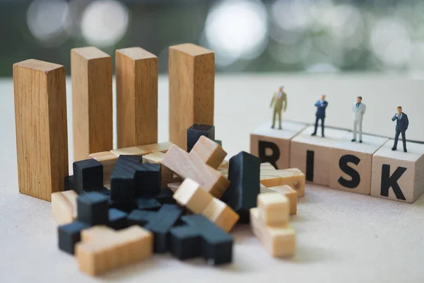 Miniature people group of businessmen stand on cube word with risk. Risk analysis for investment. The concept business risk assessment or management concept