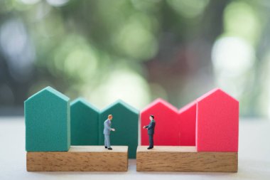 Minyatür işadamı ev arka plan ile el sıkışmak