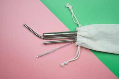 Yeniden kullanılabilir paslanmaz çelik pipetler ve pembe ve yeşil arka plan üzerinde beyaz pamuk torba içinde fırça temizleme. Çevre dostu yaşam tarzı kavramı