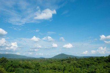 Dağlar orman, ağaçlar ve mavi gökyüzünü bulutlarla kapladı. 