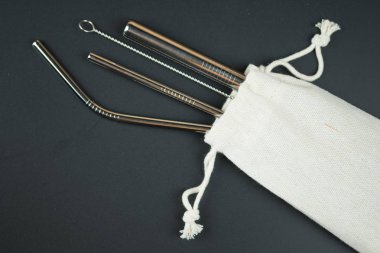 Siyah bir arka plan üzerinde mini çanta çelik içme pipetleri.