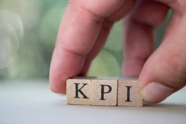 Kpi ile ahşap küp blok tutan işadamı el: Anahtar performans göstergesinin kısaltması. Kpi her yıl değerlendirme çalışmaları için aracı