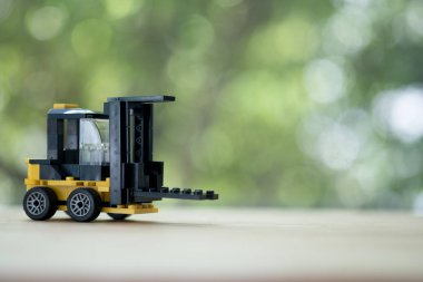 Tahta masada, arka planı bulanık minyatür sarı forklift modeli. Depo lojistik işi veya inşaat endüstrisi kavramı