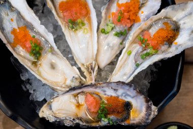 Üstünde havyar olan büyük çiğ istiridye lezzetli görünüyor.