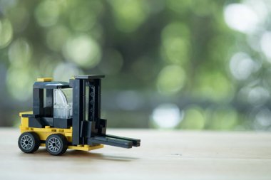 Ahşap masa üzerinde minyatür sarı forklift modeli.