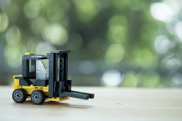 Miniature yellow forklift model on wooden table. — Stock Photo, Image