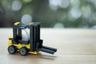 Ahşap masa üzerinde minyatür sarı forklift modeli.