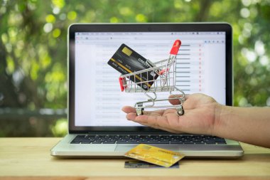 Erkek elinde kredi kartı olan bir alışveriş arabası.