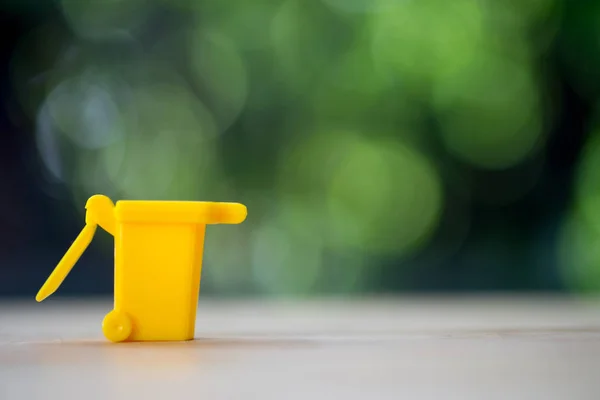 Caixa de lixo amarelo miniatura na mesa de madeira — Fotografia de Stock