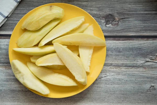 Zure onrijpe mango op de gele plaat — Stockfoto