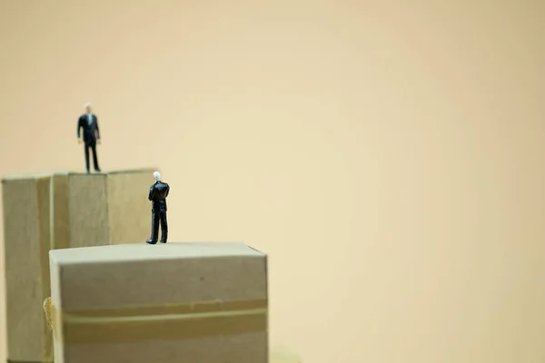 Мініатюрні люди: Бізнесмен стоїть на коричневій коробці і спілкується з партнерством. Концепція ділових переговорів — стокове фото