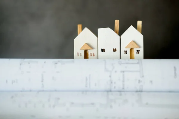 Casa em miniatura em monte de papel enrolado planos de construção — Fotografia de Stock