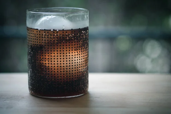 Glass of soft drink with ice ball in a glass. on wood table, soft drink